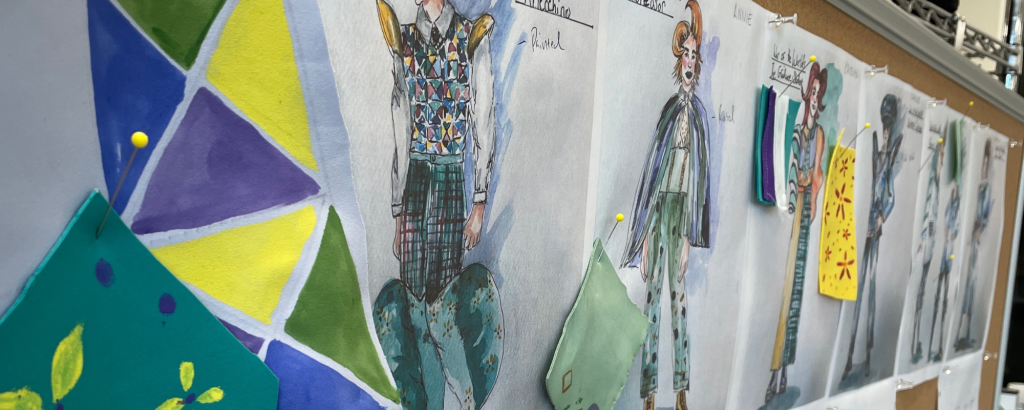 A row of costume renderings for characters in Connecticut Rep's War of the Worlds (Fall 2023) pinned to a board, along with green and yellow swatches and patterns for construction.