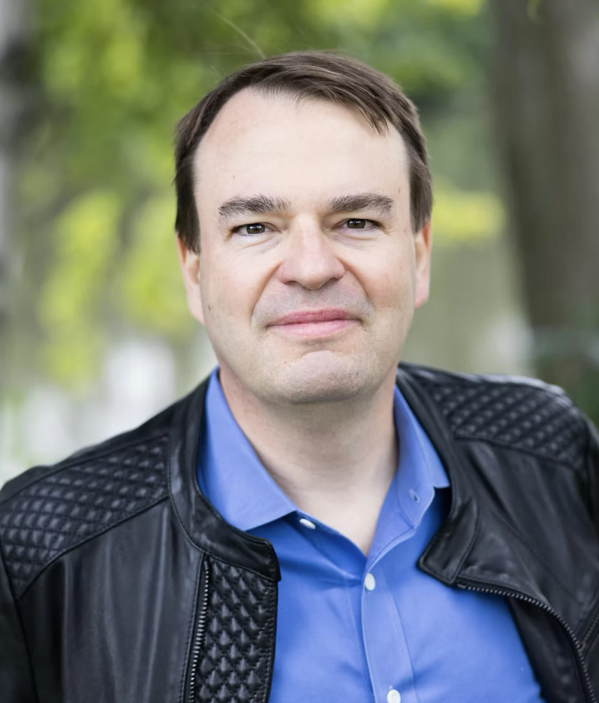 Portrait of Brendan Fox, white man with. a gentle smile looking at the camera.