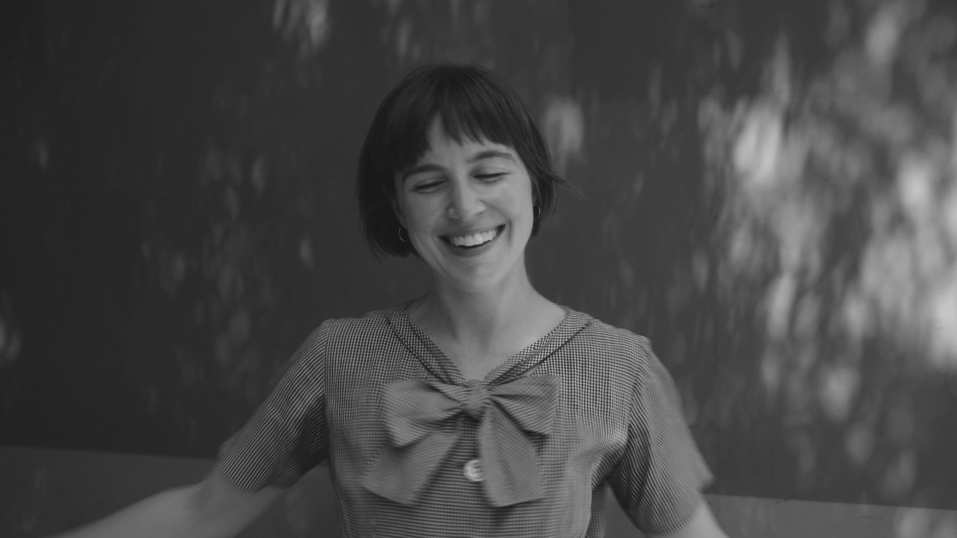 Black and white portrait of Harley Walker, a young woman with short hair and a big smile, wearing a dress with a big bow.