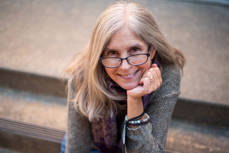 Portrait of Michelle Polgar, a white woman with glasses and a friendly smile, looking at the camera.
