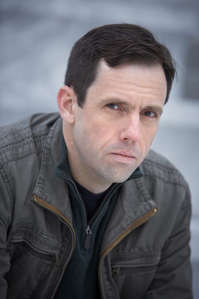 Portrait of Vince Tycer, a white man with dark hair, wearing a leather jacket