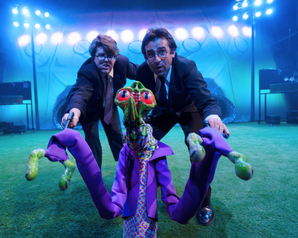 Bathed in purple light, two puppeteers animate the alien puppet for War of the Worlds 2023.
