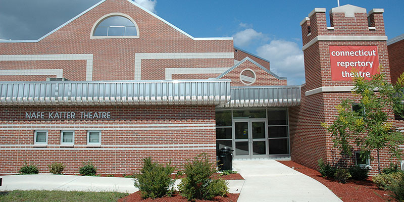 Red brick building with walkway leading to lobby doors.