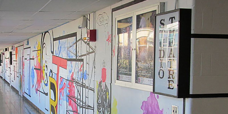 Colorful mural in a white hallway with a sign reading "Studio Theatre."