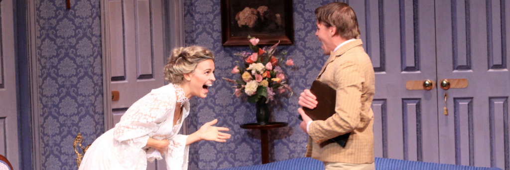 Connecticut Repertory Theatre's A Flea in Her Ear (2011) with one actor in a white dress smiling and laughing with another actor in a brown suit against a blue styled set witha bouquet of flowers in the background.