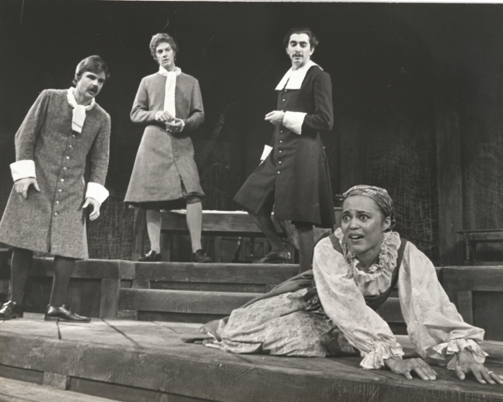 Three Puritan men look on while a young girl struggles to get off the floor.
